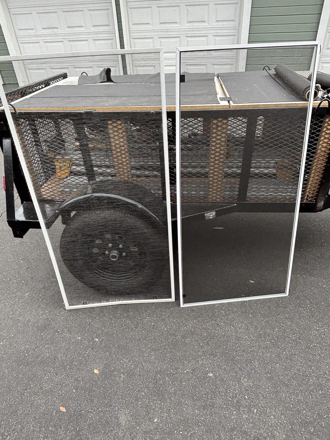 Two tall re-screened panels standing against the screen repair trailer
