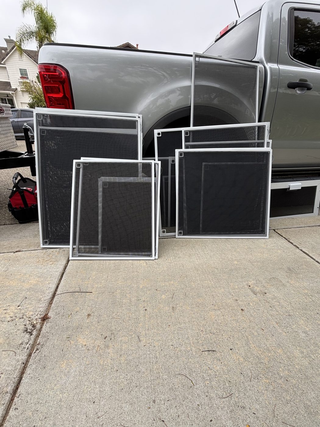 Newly finished window screens of different sizes leaning against a truck