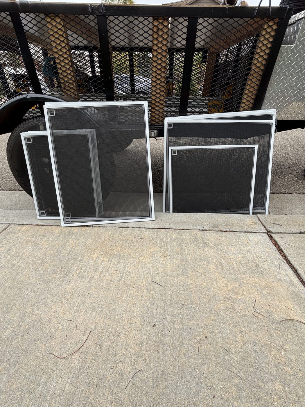 Stack of newly rebuilt window screens in the driveway